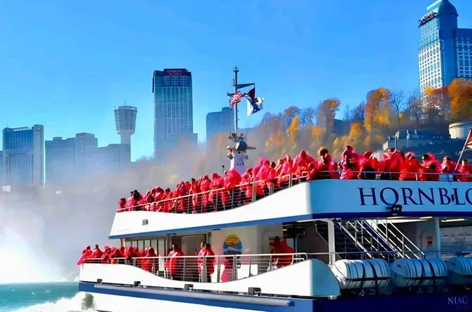 Das rote Boot von Niagara City Cruises mit Passagieren in roten Ponchos auf der kanadischen Seite